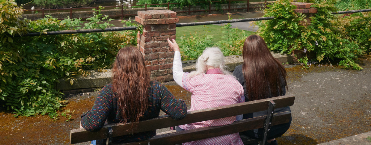 back view of a woman we support and two support workers sat on a bench overlooking a canal with two other women